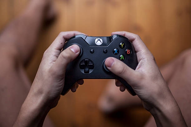 Xbox One Controller - Close Up Gothenburg, Sweden - January 06, 2015: A shot from above of a young mans hands holding a Xbox One controller as he is playing a video game. Natural lights. xbox stock pictures, royalty-free photos & images
