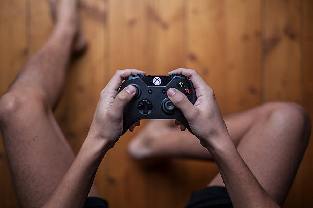 Xbox One Controller - From Above Gothenburg, Sweden - January 06, 2015: A shot from above of a young mans hands holding a Xbox One controller as he is playing a video game. Natural lights. xbox photos stock pictures, royalty-free photos & images