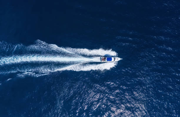 Yachts at the sea in Bali, Indonesia. Aerial view of luxury floating boat on transparent turquoise water at sunny day. Summer seascape from air. Top view from drone. Seascape with motorboat in bay. Travel - image stock photo