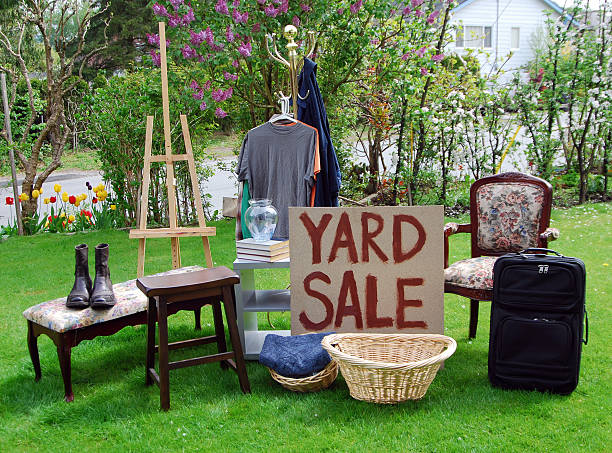 Yard sale sign on a lawn with various items stock photo