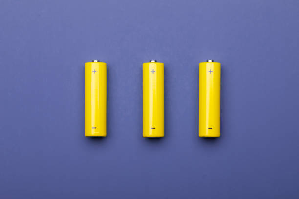Yellow AA alkaline batteries on blue trendy color of 2022 background stock photo