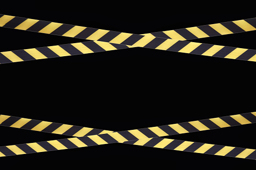 Yellow and black lines of barrier cross tape prohibit passage, tape on black isolate. Barrier that prohibits traffic. Danger unsafe area warning tape do not enter. Concept no entry. Copy space