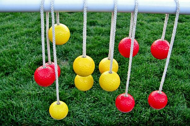 Yellow and red balls hanging on the ropes Yellow and red balls hanging on the ropes against green grass ladder stock pictures, royalty-free photos & images