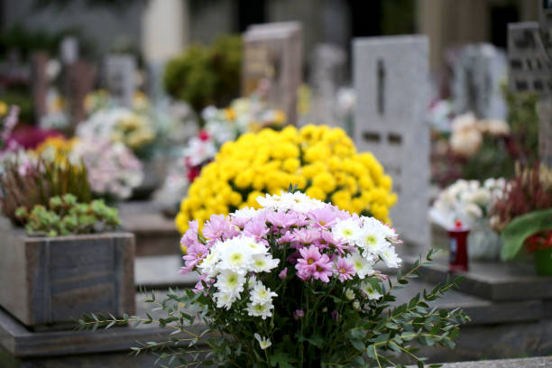 yellow and white flowers on the grave of a cemetery stock photo