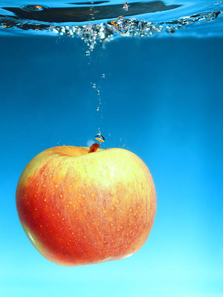 Yellow red apple in the water splash over blue background. Healthy...