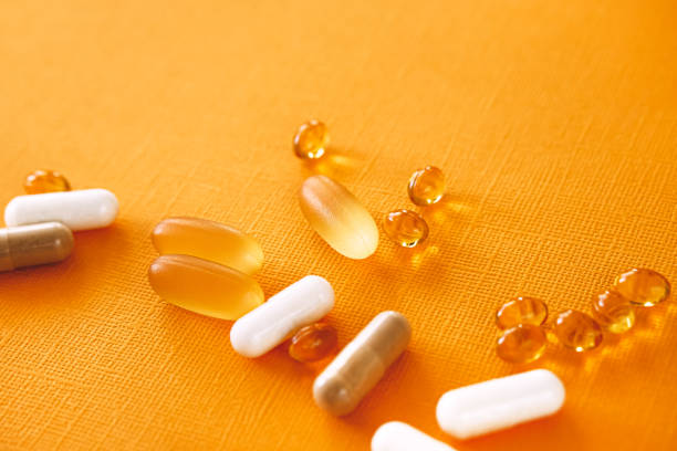 Yellow capsules of nutraceuticals in spoon. Pills and meds. stock photo