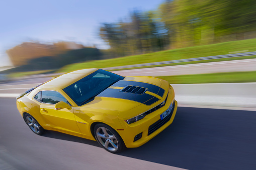 Frankfurt, Germany - May 10, 2017 : Yellow Chevrolet Camaro driving on a multiple lane highway at high speed near the city of Frankfurt in Germany on a summer day.