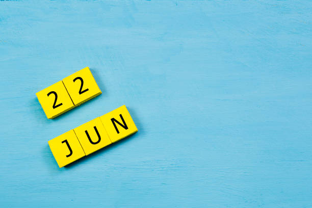 JUN 22, yellow cube calendar on blue wooden surface with copy space stock photo