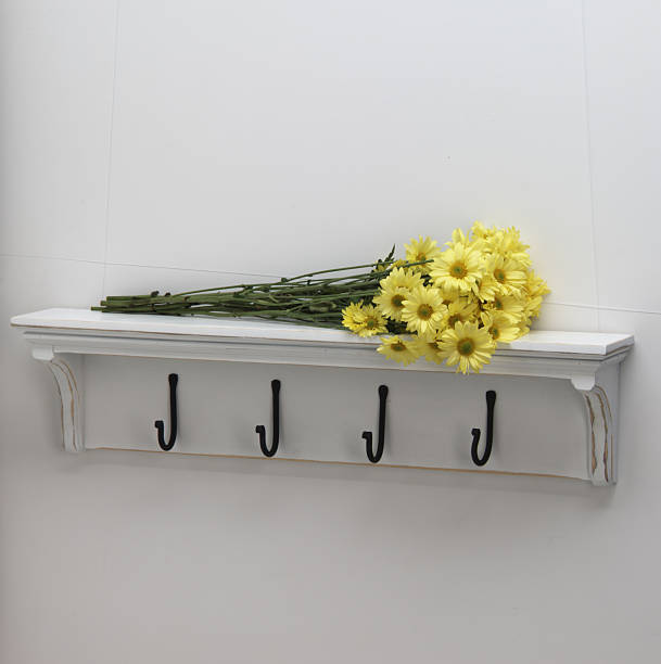 yellow daisies on white coat hook shelf stock photo