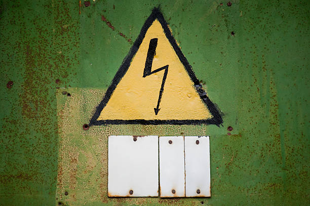 Yellow high voltage sign on aged green textured wall stock photo