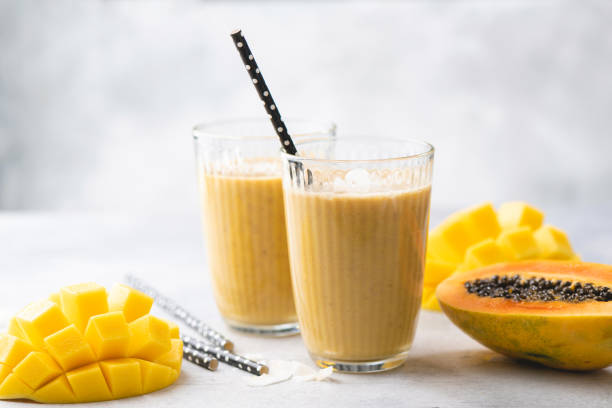 Yellow mango papaya smoothie Yellow mango papaya smoothie in glass. Tasty mango lassi papaya smoothie stock pictures, royalty-free photos & images