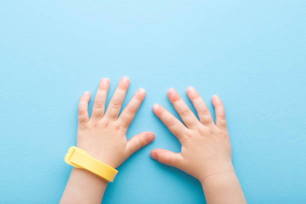 Yellow mosquito repellent band on baby wrist on light blue table background. Pastel color. Closeup. Point of view shot. Protection from insects. Top down view. stock photo