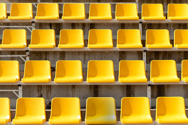gelbe plätze auf tribünen des stadions in offen. zeilen sind horizontal. auf sitzen schatten von der sonne. - stadium soccer seats stock-fotos und bilder