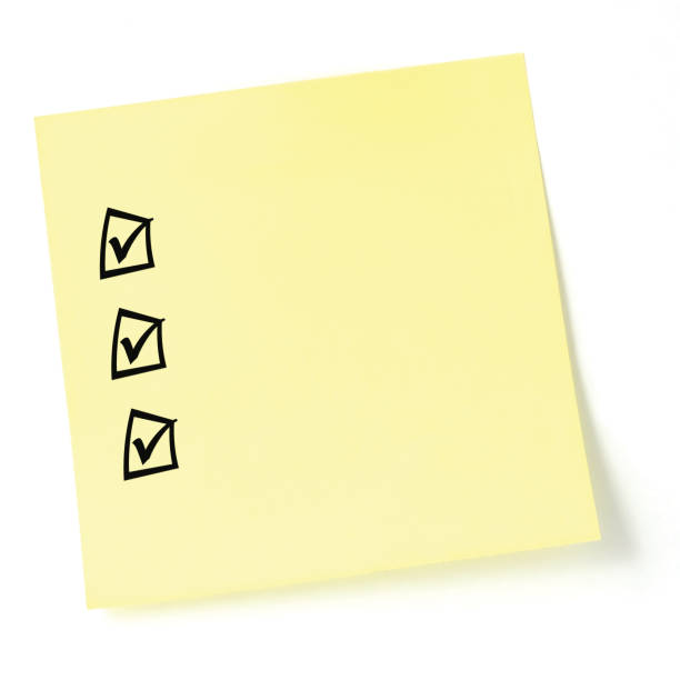 Yellow sticker checklist, black check boxes and tick marks, isolated copy space macro closeup, blank post-it to-do list sticky note stock photo