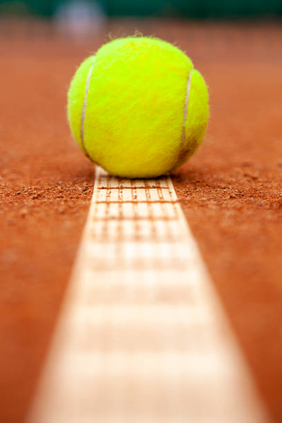 A yellow tennis ball lies on the clay court. stock photo
