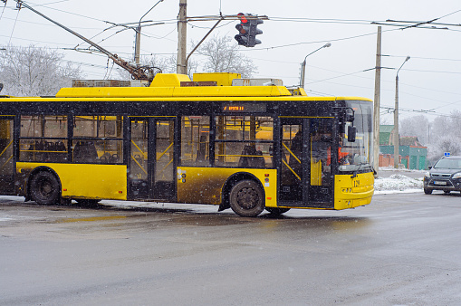 Yellow trolleybus turns around at the terminal station, it is snowing