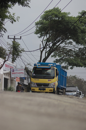 Sukabumi, West Java, Indonesia - September 22, 2020: yellow truck driving in the street in Sukabumi
