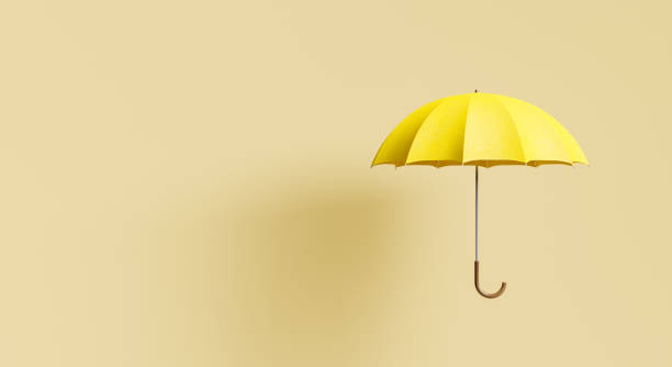 yellow umbrella on beige background with shadow stock photo