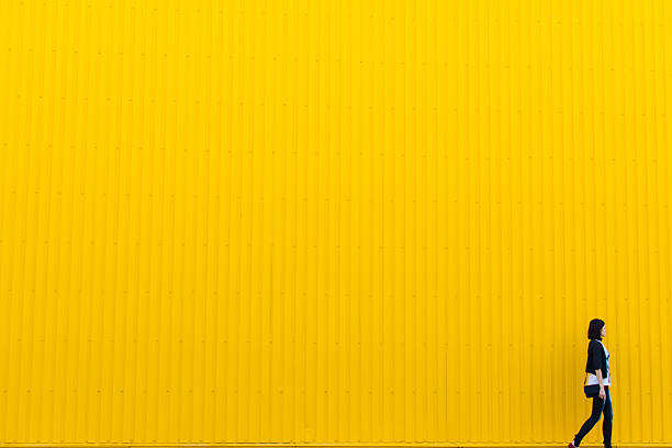 Yellow wall Girl walks near yellow wall approaching photos stock pictures, royalty-free photos & images