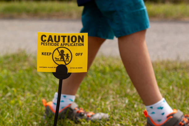 A yellow yard sign warning kids and pets of the recent pesticide spraying and advices them to stay away stock photo