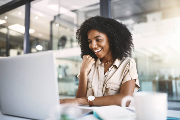 Yes! Another success Shot of a happy young businesswoman celebrating at her desk in a modern office good news stock pictures, royalty-free photos & images
