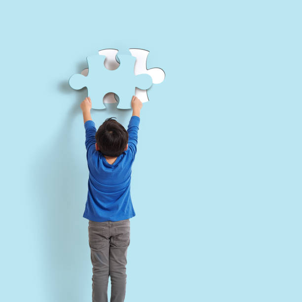 Yes, it's me! 6-7 years old child holding puzzle piece on blue background. His piece complete missing piece on wall. finishing photos stock pictures, royalty-free photos & images