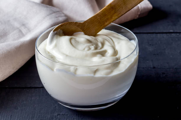 Yogurt in bowl on rustic black table - Photo of plain natural organic yoghurt close up. stock photo