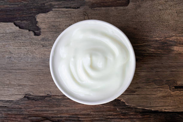 Photo of Yogurt white put in a glass put on a wooden background from top view.