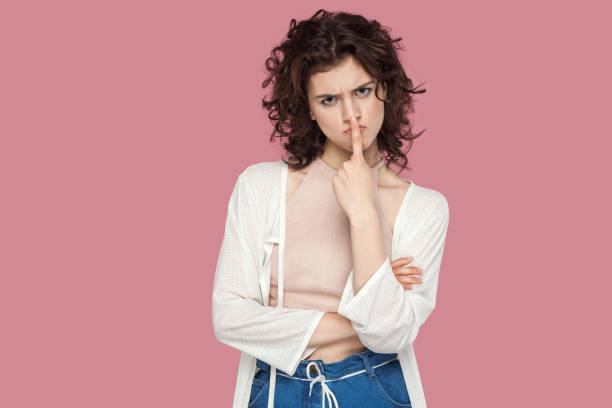 You are liar. Portrait of angry beautiful brunette young woman with curly hairstyle in casual style standing and looking at camera with lie sign. You are liar. Portrait of angry beautiful brunette young woman with curly hairstyle in casual style standing and looking at camera with lie sign. indoor studio shot isolated on pink background. ugly girl stock pictures, royalty-free photos & images