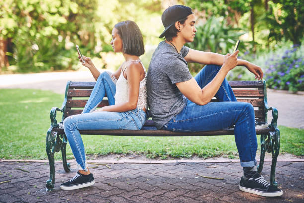You don't always have a connection with everyone you date Shot of a young couple using their cellphones while spending the day at the park bad date stock pictures, royalty-free photos & images