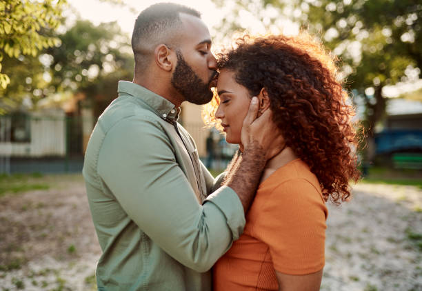 You don't cross my mind - you live in it Shot of a young man giving his girlfriend a kiss on the forehead outdoors falling in love stock pictures, royalty-free photos & images