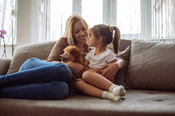 You think of a name for our new friend Shot of a mother and daughter sitting on a sofa with a cute puppy beautiful young brunette girl playing with her dog stock pictures, royalty-free photos & images