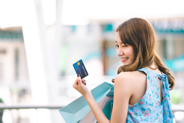 Young adult asian woman holding credit card and shopping bags. stock photo