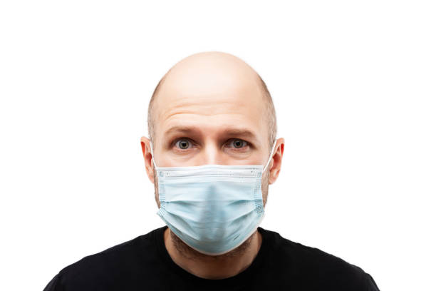 Young adult bald head man wearing respiratory protective medical mask stock photo