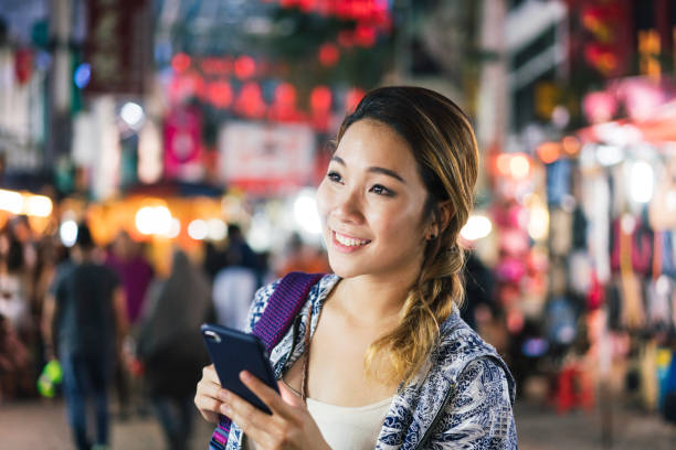Young adult chinese woman with smartphone in the city at night Young adult chinese woman with smartphone in the city at night chinatown kuala lampur stock pictures, royalty-free photos & images