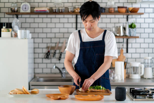 junge erwachsene männerküche allein zu hause - asiatischer koch stock-fotos und bilder