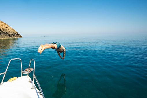 Young adult man diving from his yacht