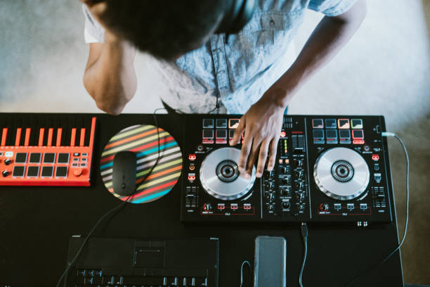 Young Adult Man Practicing His Live DJ Set at Home A young man rehearses his live music set in his apartment living room for his next disc jockey performance at a club. club dj stock pictures, royalty-free photos & images