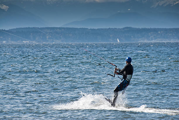 Water Skiing Behind a Parasail Seattle, Washington, USA - April 13, 2012: A young adult man water skis behind a parasail on Puget Sound. jeff goulden paragliding stock pictures, royalty-free photos & images
