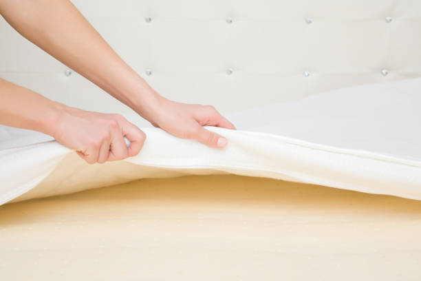 Young adult woman hands opening white cover and showing yellow rubber foam inside orthopedic mattress. Closeup. Young adult woman hands opening white cover and showing yellow rubber foam inside orthopedic mattress. Closeup. remove dirty clothes from bed stock pictures, royalty-free photos & images