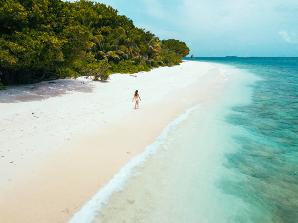 Young adult woman walking on a paradisiac beach in Maldives stock photo