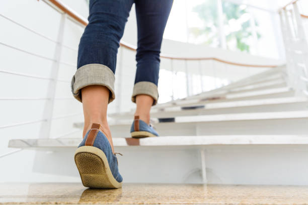 Young adult woman walking up the stairs with sun sport background. stock photo