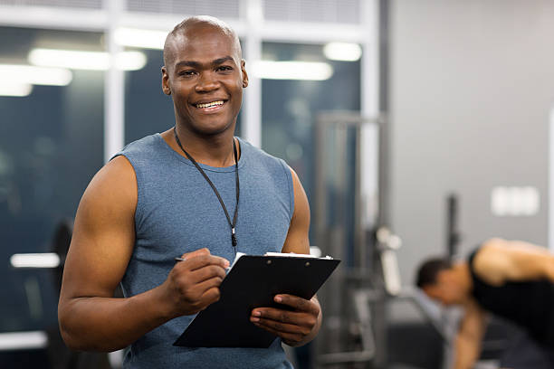 young african american male personal trainer young african american male personal trainer holding clipboard in gym athleticism stock pictures, royalty-free photos & images