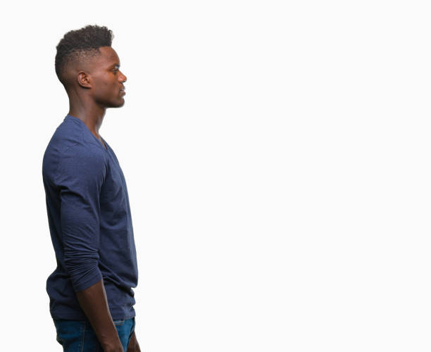 Young african american man over isolated background looking to side, relax profile pose with natural face with confident smile. Young african american man over isolated background looking to side, relax profile pose with natural face with confident smile. lateral surface photos stock pictures, royalty-free photos & images