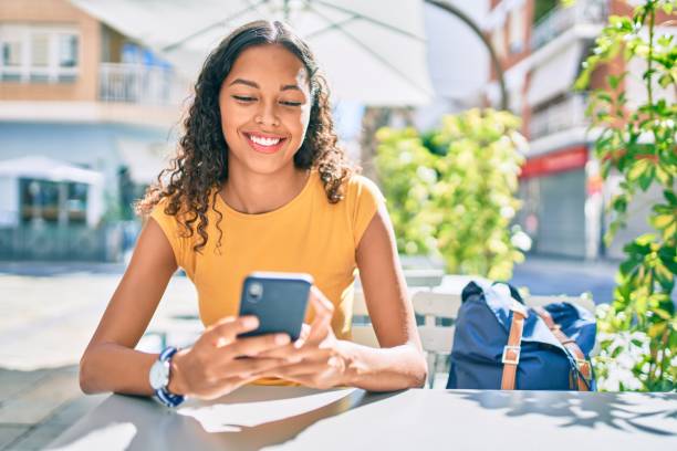 Young african american student girl smiling happy using smartphone. stock photo