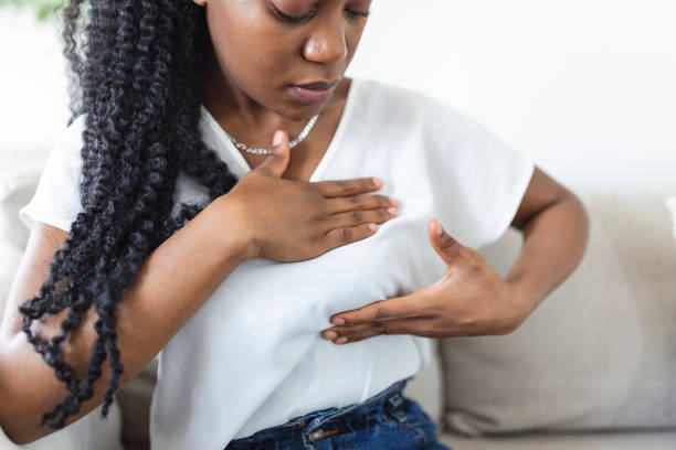 Young African American woman palpating her breast by herself that she concern about breast cancer. Healthcare and breast cancer concept stock photo