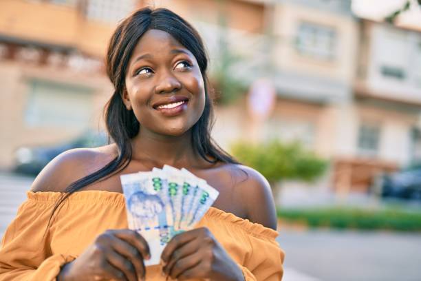 Young african american woman smiling happy holding south africa rands at the city. stock photo
