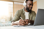istock Young african man using computer laptop while wearing headphones at bar restaurant - Conference video call lifestyle technology concept - Focus on face 1331818654
