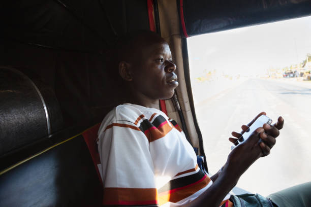 Young african man using mobile phone inside taxi stock photo