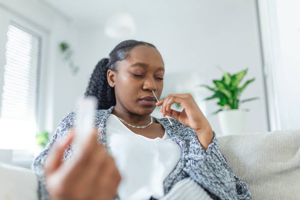 młoda afrykańska kobieta posiadająca samokontrolę samokontroli wacika i rurki medycznej dla coronavirus covid-19, zanim zostanie przebadany w domu - at home covid test zdjęcia i obrazy z banku zdjęć